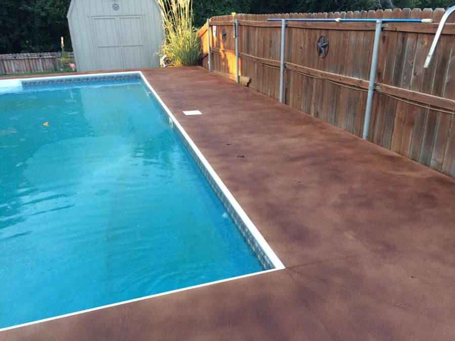 small stained concrete pool deck with wood fences in Fort Worth TX